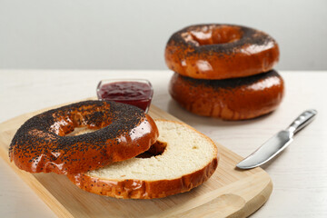 Delicious fresh bagels with poppy seeds and jam on white wooden table