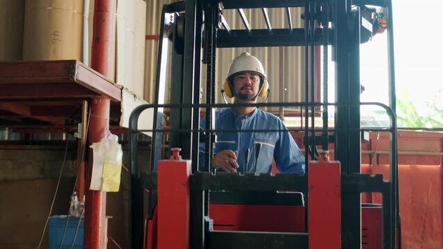 Safety uniform male Asian industrial worker and hard hat use hydraulic forklift truck, shipping, and logistic transport at warehouse manufacture factory, supply stocks professional driver occupation.