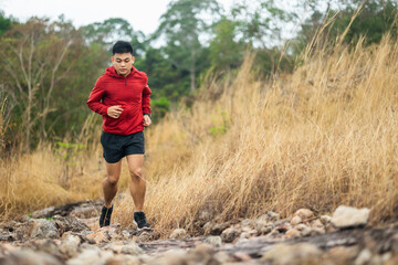 Trail runner man running on rocky mountain. Athlete jog exercising outdoor for healthy. Confident and powerful marathon man running workout and cardio. Sport and Lifestyle concept.