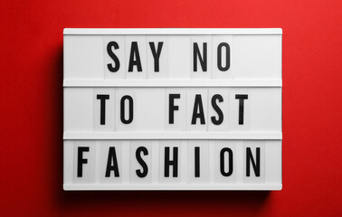 Lightbox with phrase SAY NO TO FAST FASHION on red background, top view