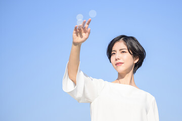 目標や未来の何かに使えそうな空に何かを描く女性