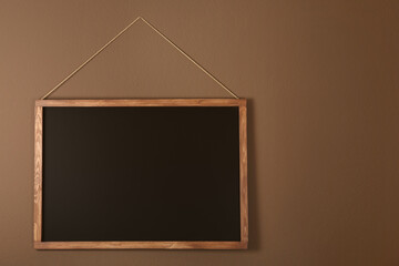 Clean black chalkboard hanging on brown wall