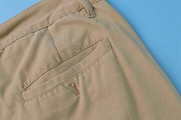 Close up view of a man's pant pocket isolated on a blue background