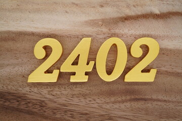Golden Arabic numerals on a real brown and white wooden floor number 2402
