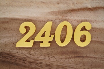 Golden Arabic numerals on a real brown and white wooden floor number 2406