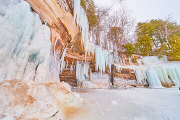 Fototapeta na wymiar Cliffs on lake in winter covered in large blue ice formations and icicles