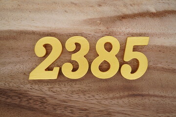 Golden Arabic numerals on a real brown and white wooden floor number 2385