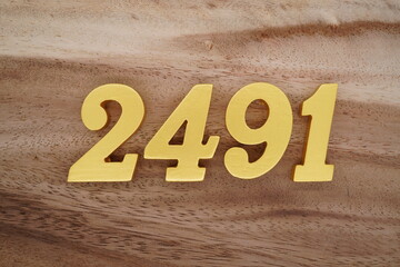 Golden Arabic numerals on a real brown and white wooden floor number 2491