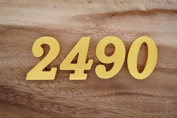 Golden Arabic numerals on a real brown and white wooden floor number 2490