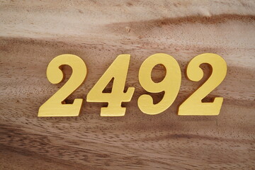 Golden Arabic numerals on a real brown and white wooden floor number 2492