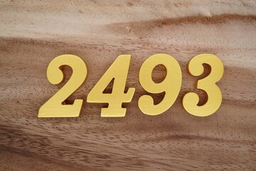 Golden Arabic numerals on a real brown and white wooden floor number 2493