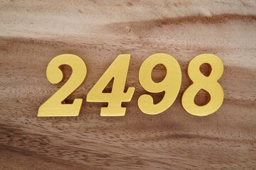 Golden Arabic numerals on a real brown and white wooden floor number 2498