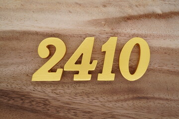 Golden Arabic numerals on a real brown and white wooden floor number 2410