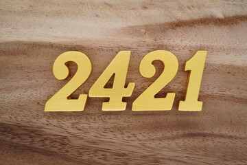 Golden Arabic numerals on a real brown and white wooden floor number 2421