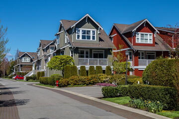 Fototapeta na wymiar Residential District in Richmond City, a village of townhouses , green grass bushes and trees in the territory of residential complex, blue sky, Vanсouver, British Columbia 