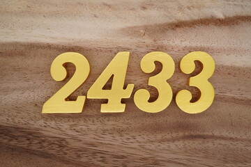 Golden Arabic numerals on a real brown and white wooden floor number 2433