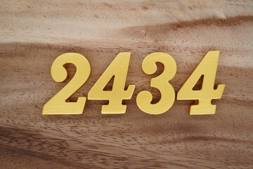 Golden Arabic numerals on a real brown and white wooden floor number 2434