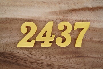 Golden Arabic numerals on a real brown and white wooden floor number 2437