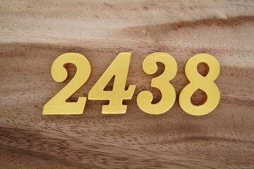 Golden Arabic numerals on a real brown and white wooden floor number 2438