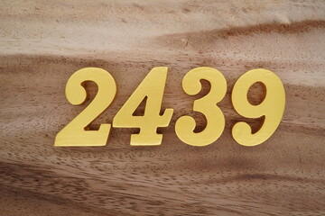 Golden Arabic numerals on a real brown and white wooden floor number 2439