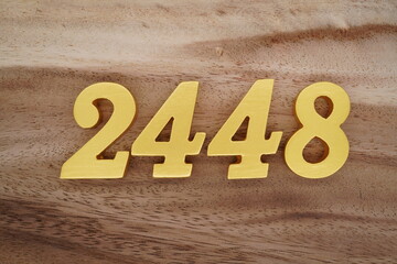 Golden Arabic numerals on a real brown and white wooden floor number 2448