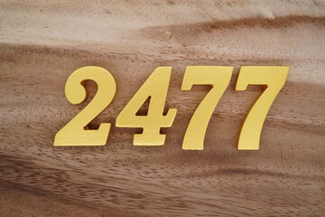 Golden Arabic numerals on a real brown and white wooden floor number 2477