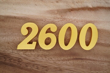 Golden Arabic numerals on a real brown and white wooden floor number 2600