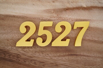 Golden Arabic numerals on a real brown and white wooden floor number 2527