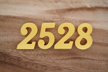 Golden Arabic numerals on a real brown and white wooden floor number 2528