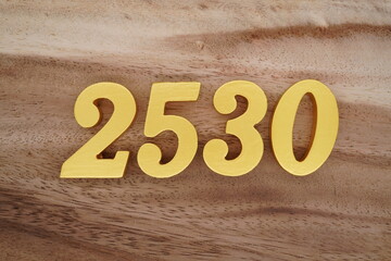 Golden Arabic numerals on a real brown and white wooden floor number 2530