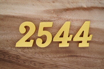 Golden Arabic numerals on a real brown and white wooden floor number 2544