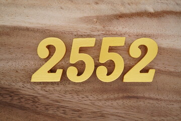 Golden Arabic numerals on a real brown and white wooden floor number 2552