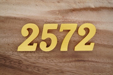Golden Arabic numerals on a real brown and white wooden floor number 2572