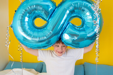 The inflatable figure 8 is in the hands of a contented happy boy. A boy in his room is playing with...