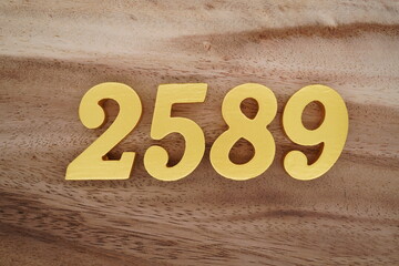 Golden Arabic numerals on a real brown and white wooden floor number 2589