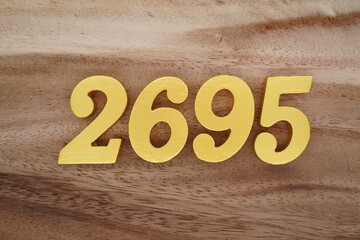 Golden Arabic numerals on a real brown and white wooden floor number 2695