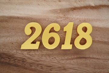 Golden Arabic numerals on a real brown and white wooden floor number 2618