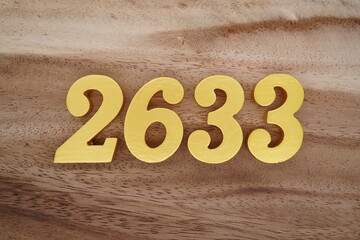 Golden Arabic numerals on a real brown and white wooden floor number 2633