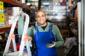 Portrait of a worker in overalls at the warehouse of a hardware store