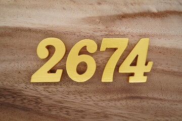 Golden Arabic numerals on a real brown and white wooden floor number 2674
