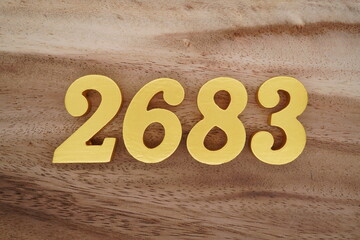 Golden Arabic numerals on a real brown and white wooden floor number 2683