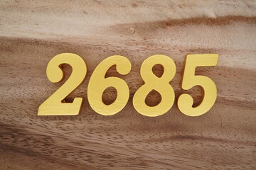 Golden Arabic numerals on a real brown and white wooden floor number 2685