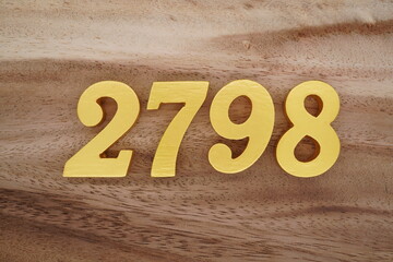 Golden Arabic numerals on a real brown and white wooden floor number 2798