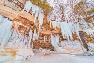 Colorful cliff wall on frozen lake covered in sharp blue icicles - Powered by Adobe