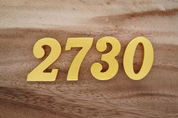 Golden Arabic numerals on a real brown and white wooden floor number 2730