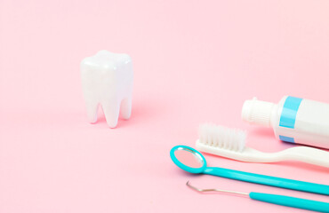 tooth mockup and dental instruments on pink background