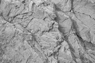 Black white rock texture. Cracked layered mountain surface. Close-up. Gray grungy stone background...