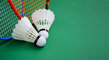 Cream white badminton shuttlecock and rackets on green floor in indoor badminton court, soft and selective focus, copy space, concept for badminton lovers around the world.