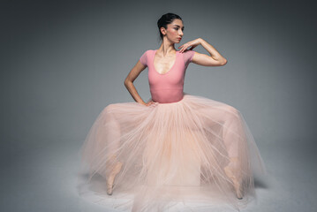 young pretty, fragile, beautiful ballerina dancing in a long pale pink dress with tulle on a uniform background, hand movements, restrained tone. Ballet, dance, dancer. Place for inscription