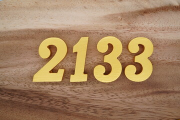 Golden Arabic numerals on a real brown and white wooden floor number 2133